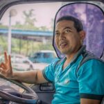 נהג אוטובוס מחייך יושב מאחורי ההגה